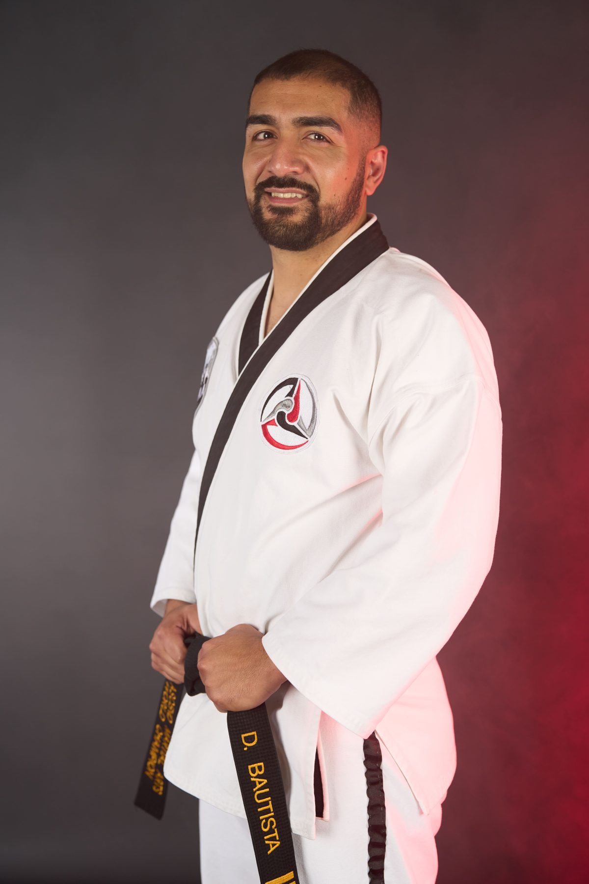 Mr. Daniel Bautista poses with hands on his black belt wearing his white uniform